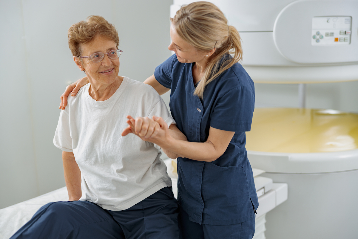 Female doktor helping female patient sit after procedure of MRI or CT Scan