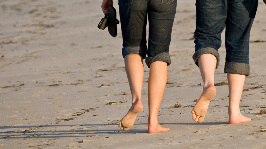 Bild på fötterna hos två personer som promenerar vid havet.