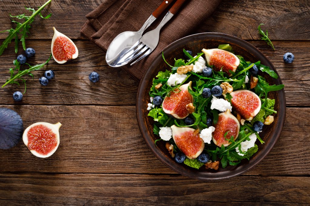 Bild på skål fylld med sallad toppad med färska fikon och blåbär.