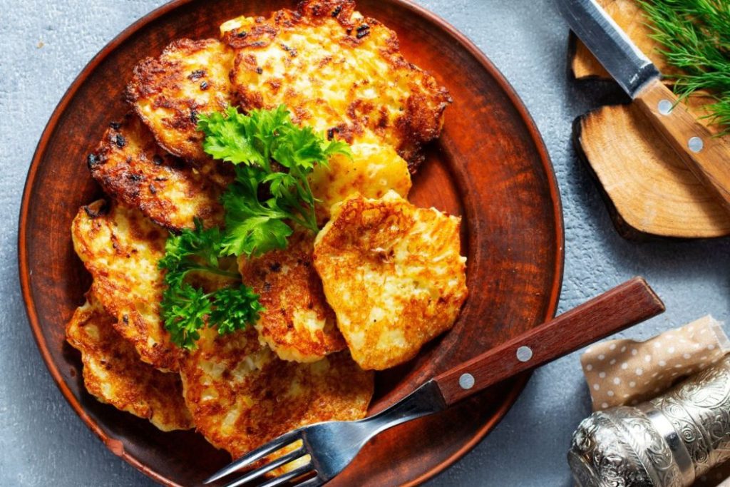 En brun tallrik med rårakor av potatis, toppade med persilja