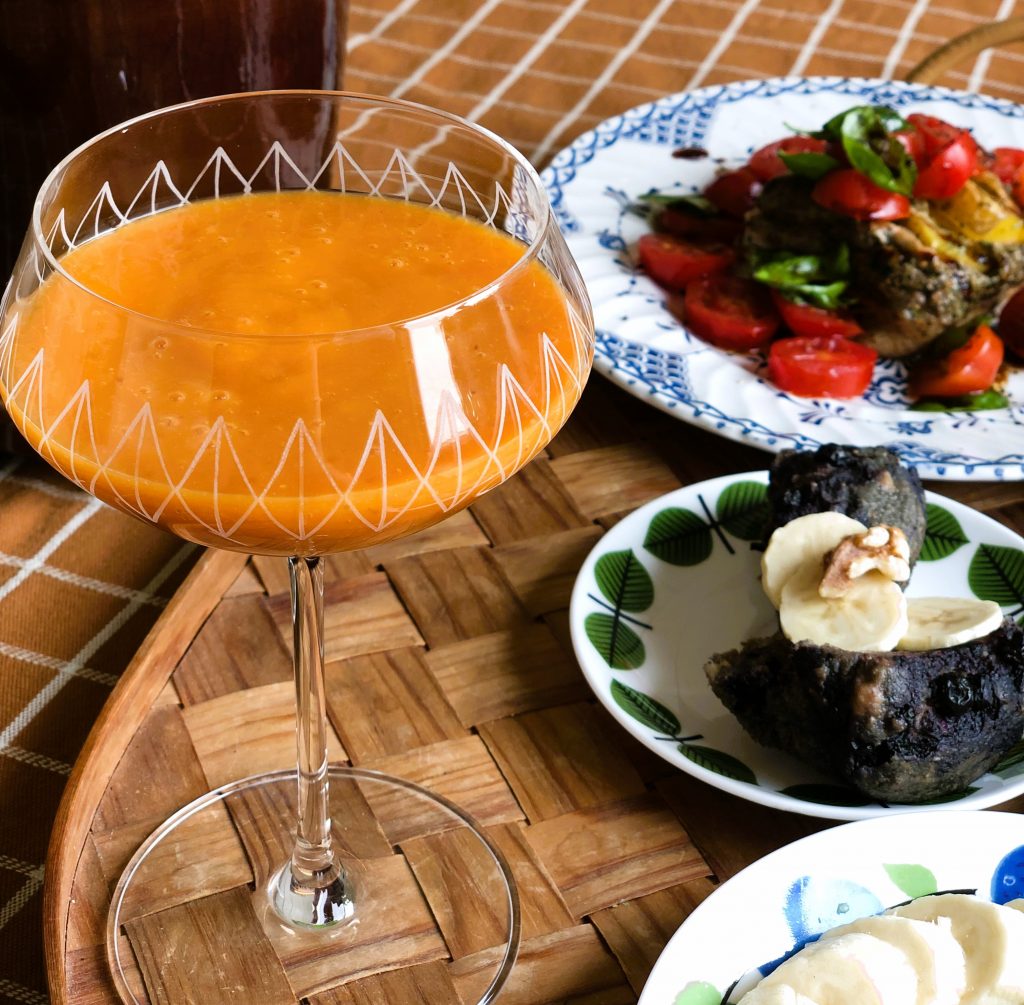 Bild på orange smoothie i högt glas och på muffins och tomatsallad.