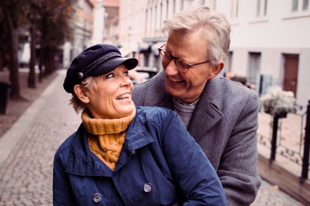 Man och kvinna, ca 60 år, håller om varandra ute på en kullerstensgata