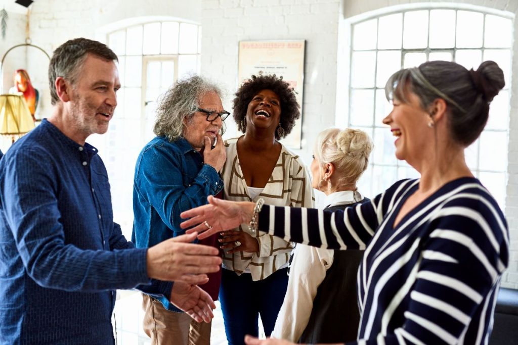 En grupp vänner i medelålderna hälsar glatt på varandra på en fest