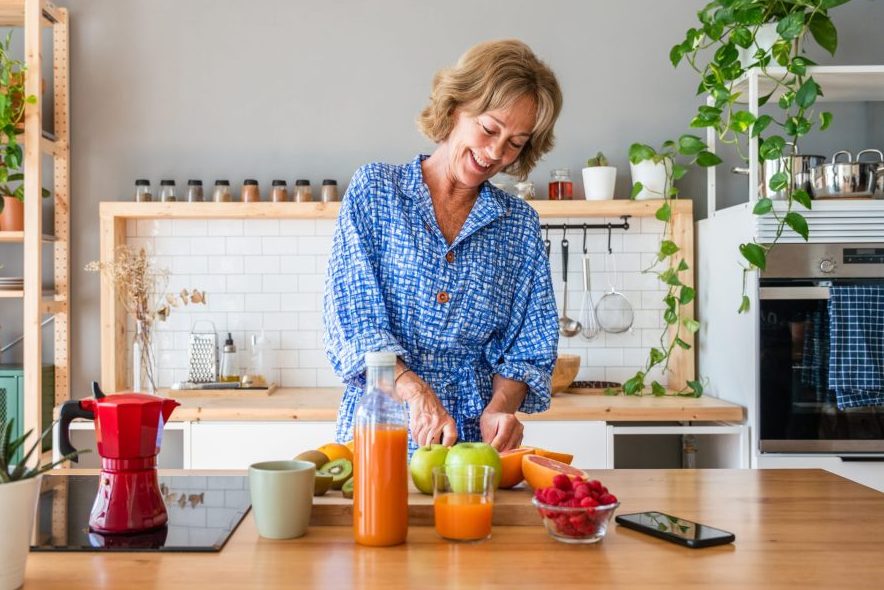 Beautiful mature senior woman at home, domestic life and leisure moments - 50-60 years old pretty female adult cooking healthy food at home in the kitchen for diet