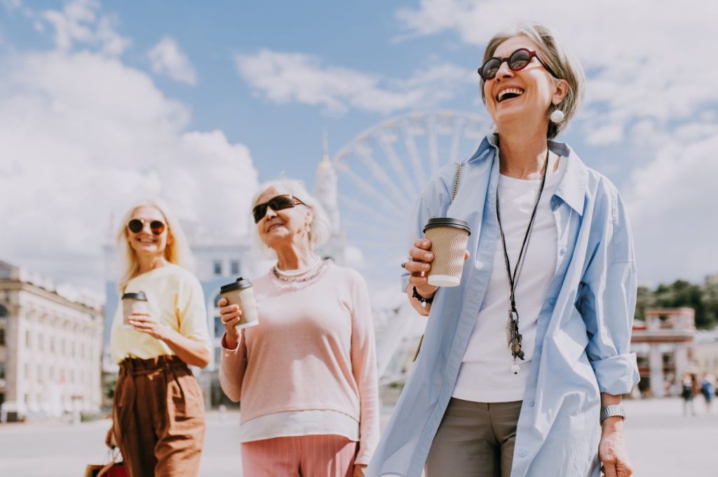 En grupp äldre kvinnor tar en promenad och dricker kaffe i solen